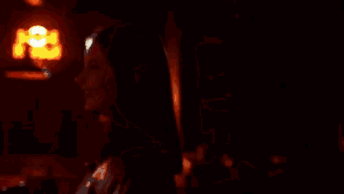 a close up of a woman 's face in a dark room with a red light behind her .