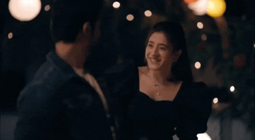 a man and a woman are dancing together in a dark room with lights in the background .