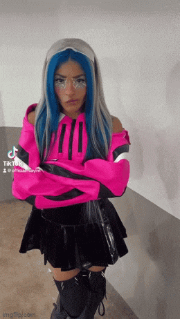 a woman with blue hair is wearing a pink jacket and black skirt