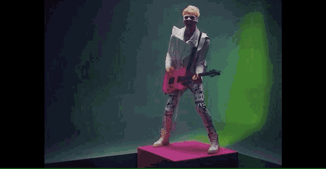 a man with a bandage on his face is playing a pink guitar .