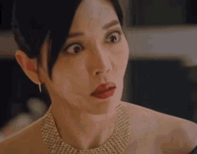 a woman wearing a necklace and earrings is making a surprised face .