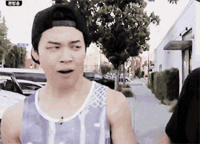 a man wearing a hat and a tank top is walking down a sidewalk