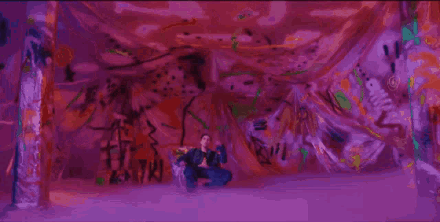 a man is sitting on a couch in a dark room with a purple light behind him .