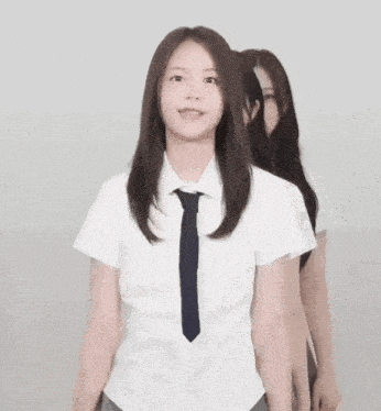 a girl in a school uniform making a heart shape with her hands .