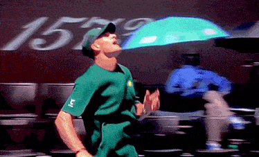 a man in a green shirt is holding an umbrella in front of a sign that says 1570