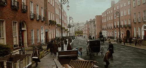 a group of people walking down a street with a horse drawn carriage in the foreground