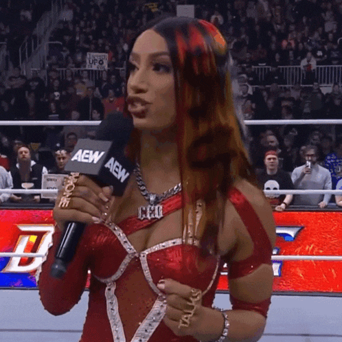 a woman in a red dress is holding a microphone that says aew on it
