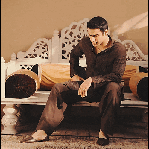 a man in a brown shirt sits on a white bench