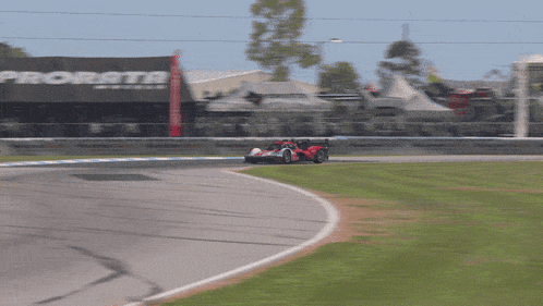 a race car is going around a curve in front of a prorata sign