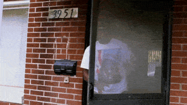 a man stands in front of a brick building with a sign that says ' 39 51 '