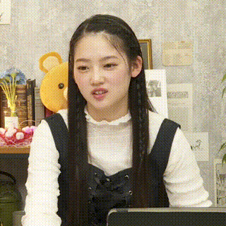 a woman with long hair is sitting in front of a laptop computer and making a funny face .