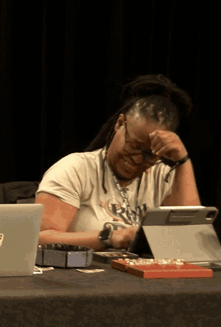 a woman with dreadlocks is sitting at a table with a tablet