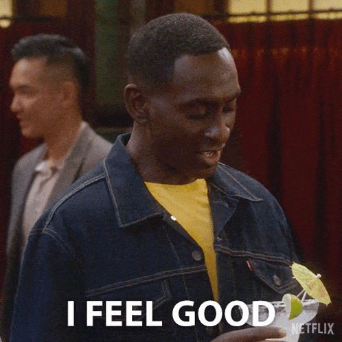 a man in a denim jacket is holding a cocktail and says i feel good .