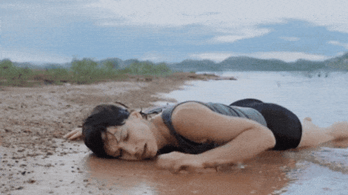 a woman is laying on the beach looking at the water