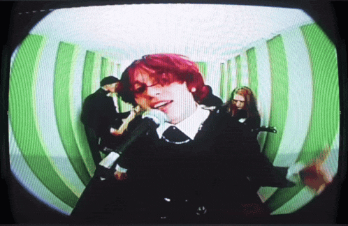 a woman with red hair is singing into a microphone in a green and white room