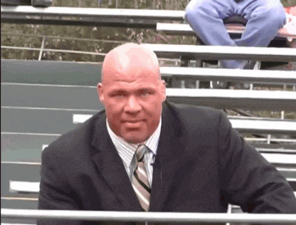 a man in a suit and tie is sitting in a stadium