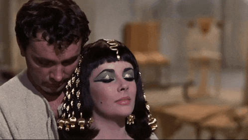 a man and a woman are standing next to each other and the woman is wearing green eyeshadow