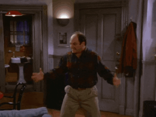 a bald man is dancing in a living room with his arms outstretched