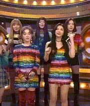 a group of women standing next to each other wearing rainbow colored dresses