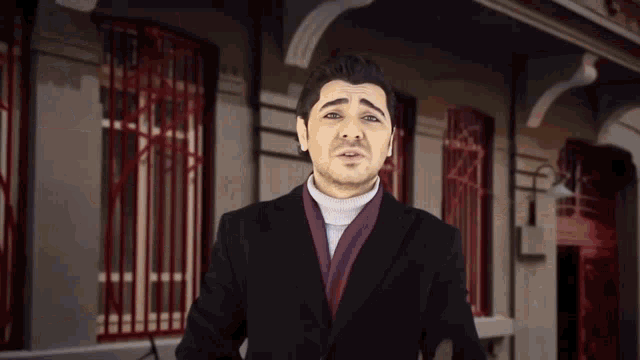 a man in a black coat stands in front of a building
