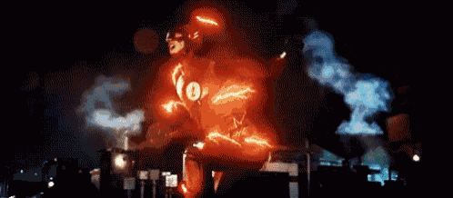 a man in a flash costume is standing on a street at night .