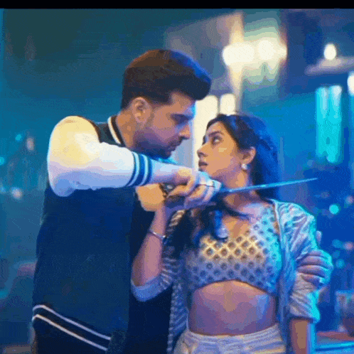 a man is holding a knife to a woman 's neck in a dark room .