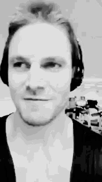 a man wearing headphones is smiling in a black and white photo .