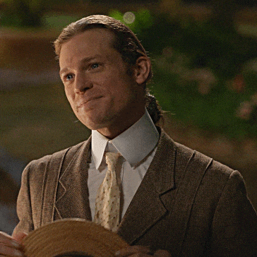 a man in a suit and tie holds a straw hat in his hands