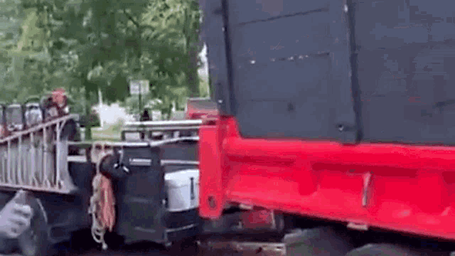 a red truck is parked next to a black truck in a parking lot .