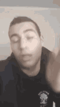 a close up of a man 's face with his eyes closed and his hand up .