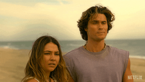 a man and a woman standing on a beach with a netflix logo on the bottom