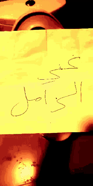 a piece of paper with arabic writing on it is being held up