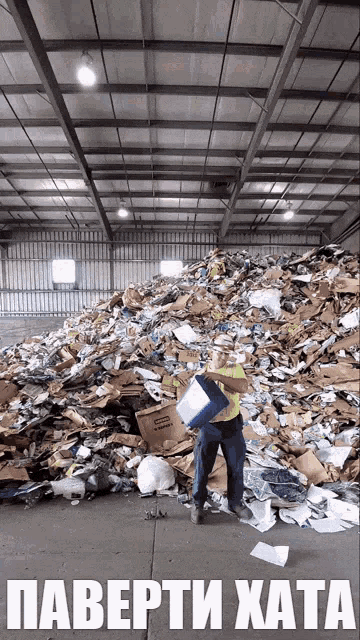 a man is standing in front of a pile of cardboard boxes with the words паверти хата written below him