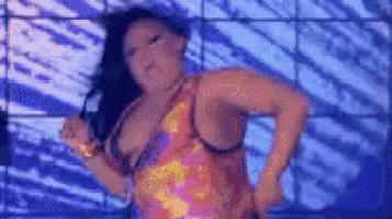a woman in a colorful dress is dancing on a stage in front of a blue wall .
