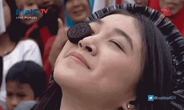 a woman is eating an oreo cookie in front of a mnctv logo