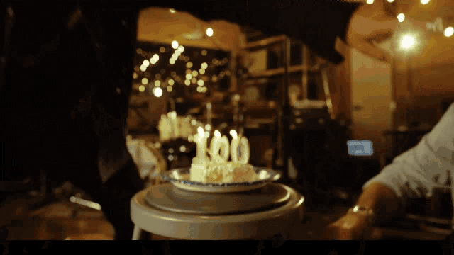 a cake with 100 candles on it is on a stool