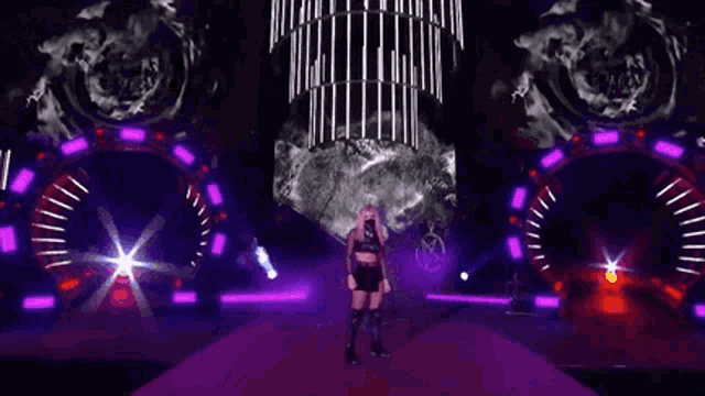 a woman wearing a mask is standing on a stage in front of a purple background .