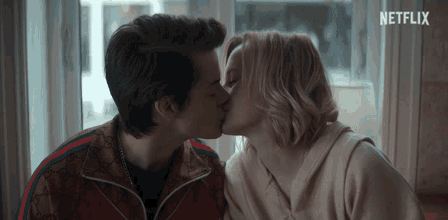 a man and a woman are kissing in front of a netflix sign