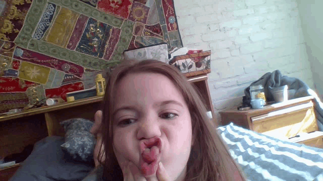 a young girl is making a funny face with her tongue out