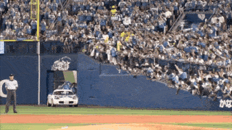 a baseball field with a car in front of a crowd and a sign that says ' a ' on it