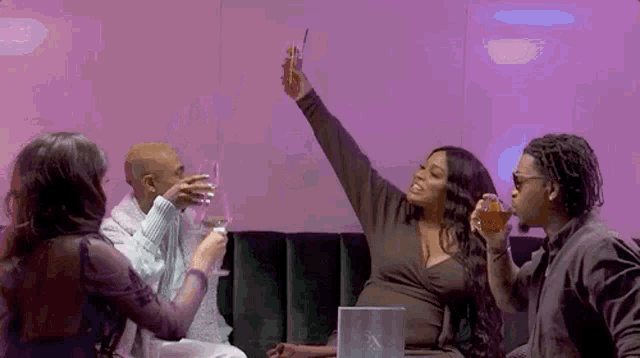 a group of people are sitting on a couch holding drinks and toasting .