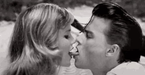 a man and a woman are kissing each other in a black and white photo .