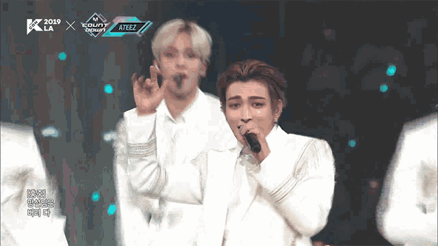 a man singing into a microphone in front of a sign that says ' ateez '