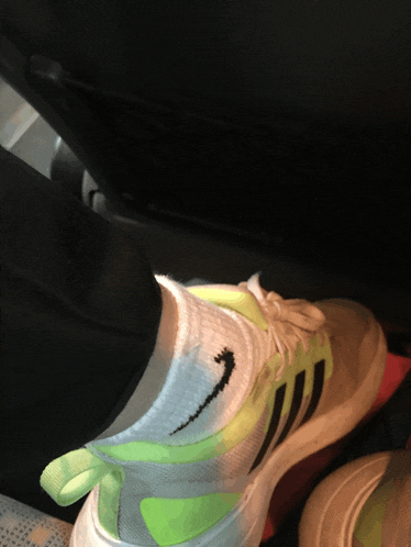 a person wearing a pair of neon green and white adidas sneakers