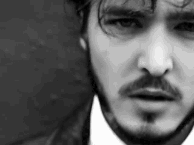 a black and white photo of a man 's face with a beard