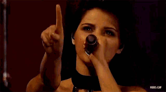 a woman singing into a microphone with rbd.gif written on the bottom