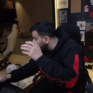 a man wearing a black and red hoodie is sitting in a chair
