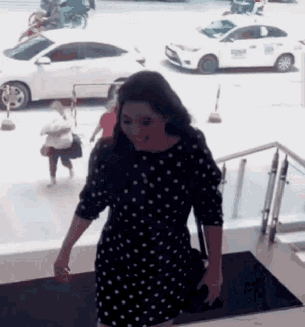 a woman in a black and white polka dot dress is walking down a set of stairs