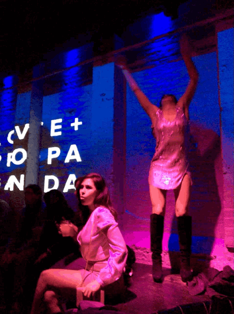 two women are dancing in front of a wall that says cv e + ro pa en da
