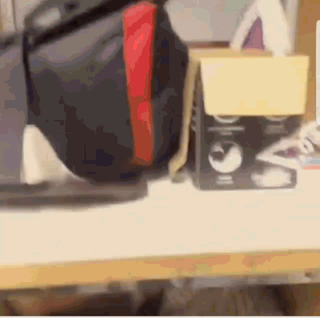 a blurred image of a desk with a bag and a box that says ' o ' on it